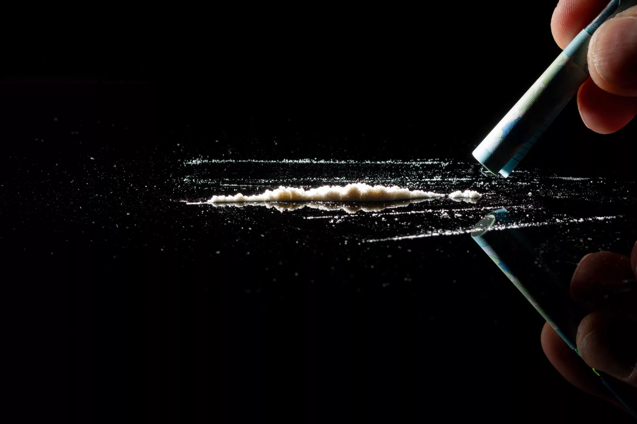 Line of cocaine powder on a dark surface representing cocaine use and addiction risks