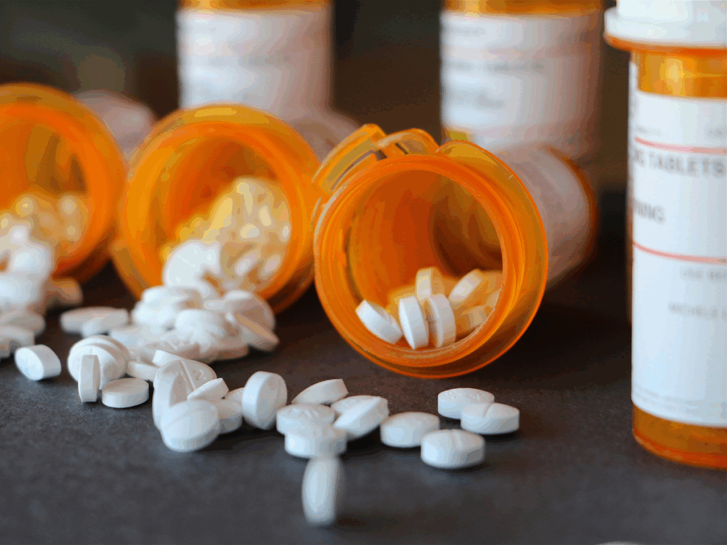 Prescription drugs spilling out of their orange bottle from someone with a prescription pill addiction who needs rehab