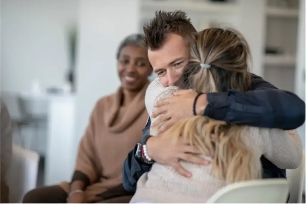 Clients sharing a supportive hug during a group therapy session at a luxury addiction treatment center in Los Angeles, California, emphasizing emotional healing and compassionate recovery.